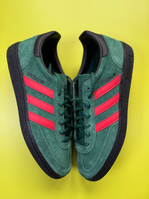 A pair of green suede Adidas Samba sneakers with red three-stripes and black soles