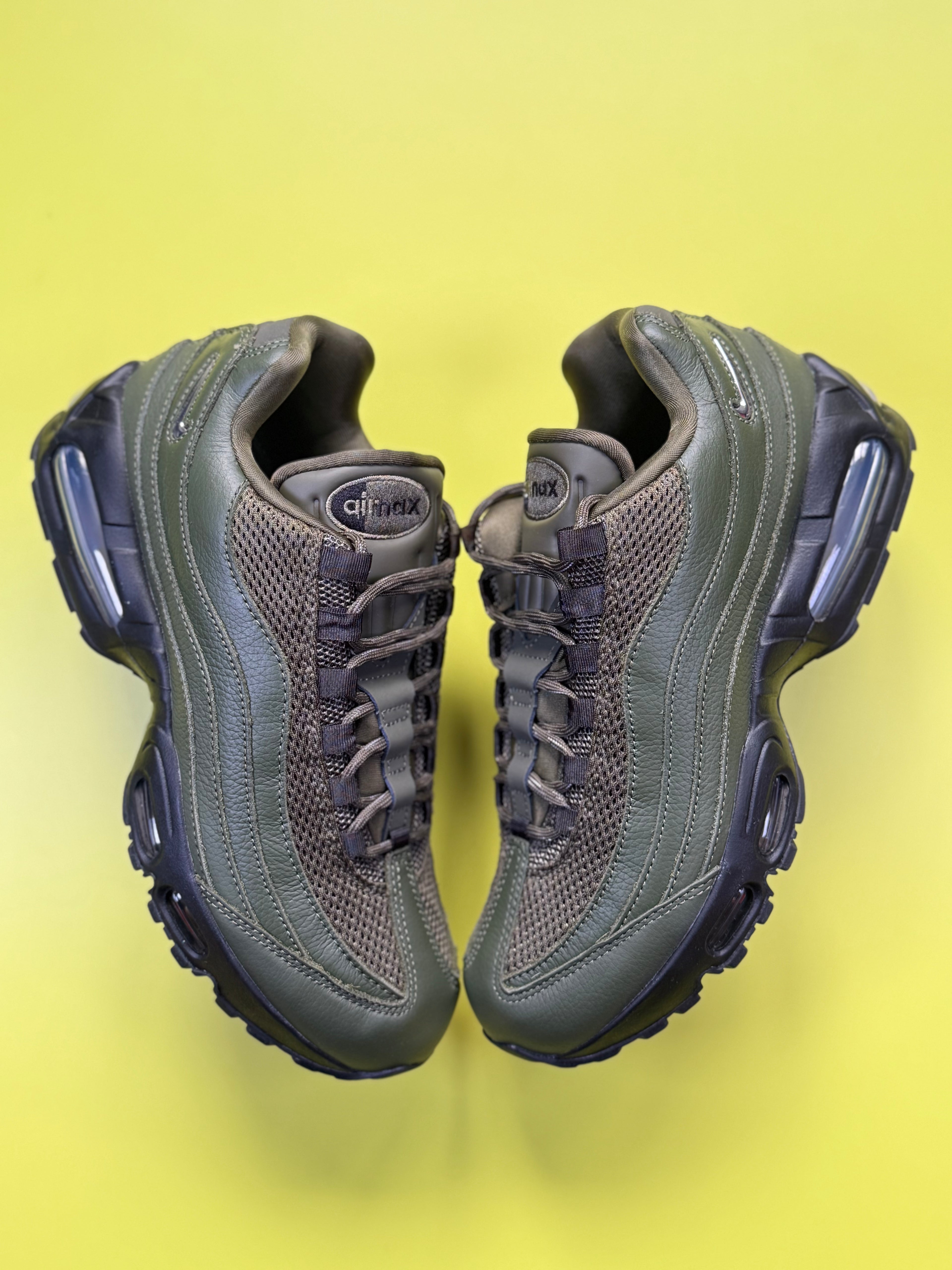 A pair of Nike Air Max 95 sneakers in olive green and dark gray